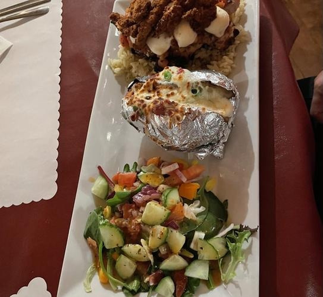 Une assiette avec poulet pané, pomme de terre au four garnie et salade fraîche